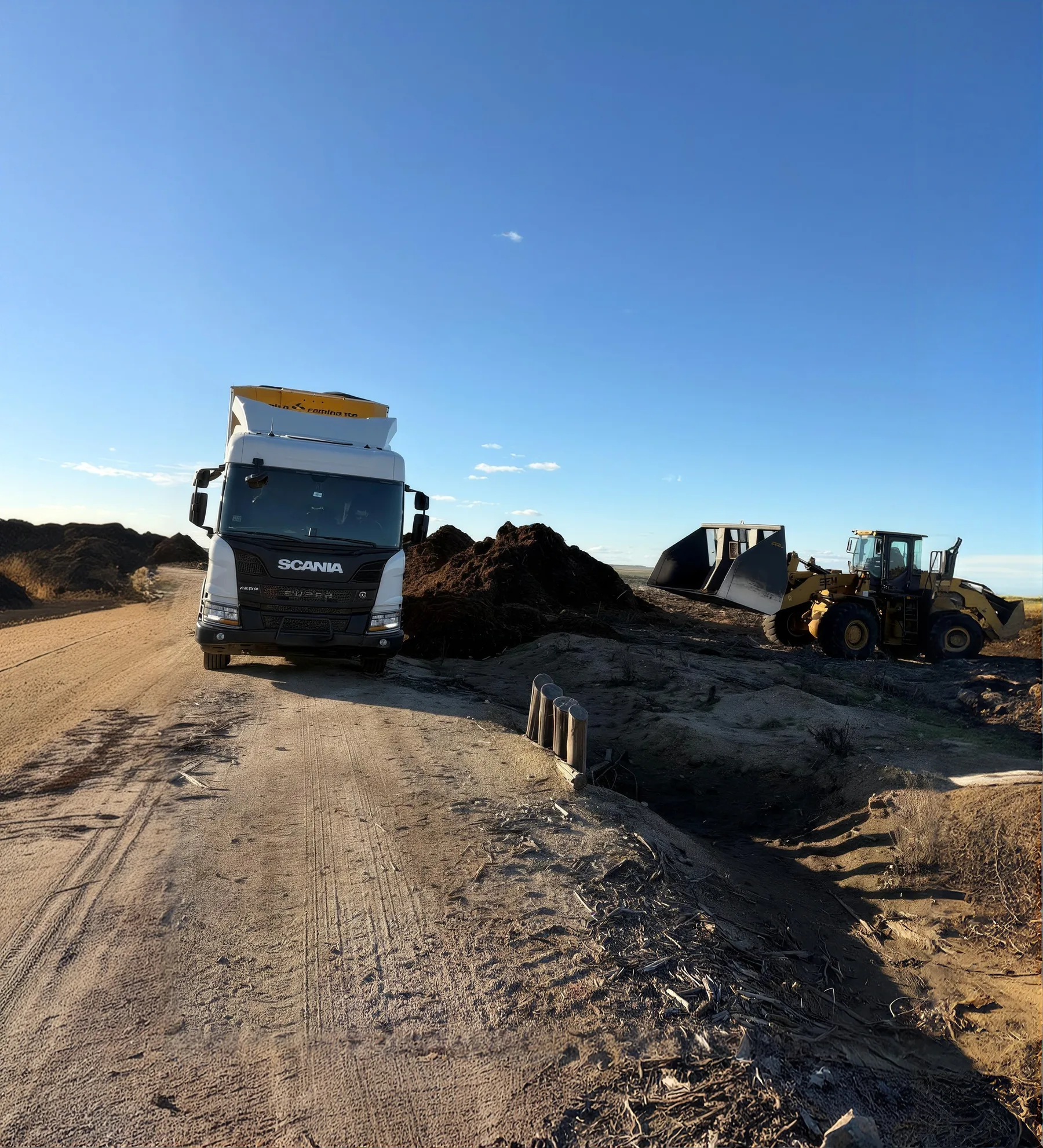 Camión de transporte junto a una pila de biomasa
